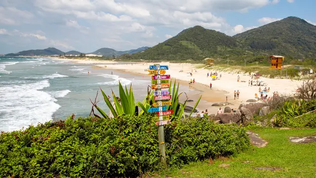 Placa colorida na praia com morros ao fundo, em Garopaba