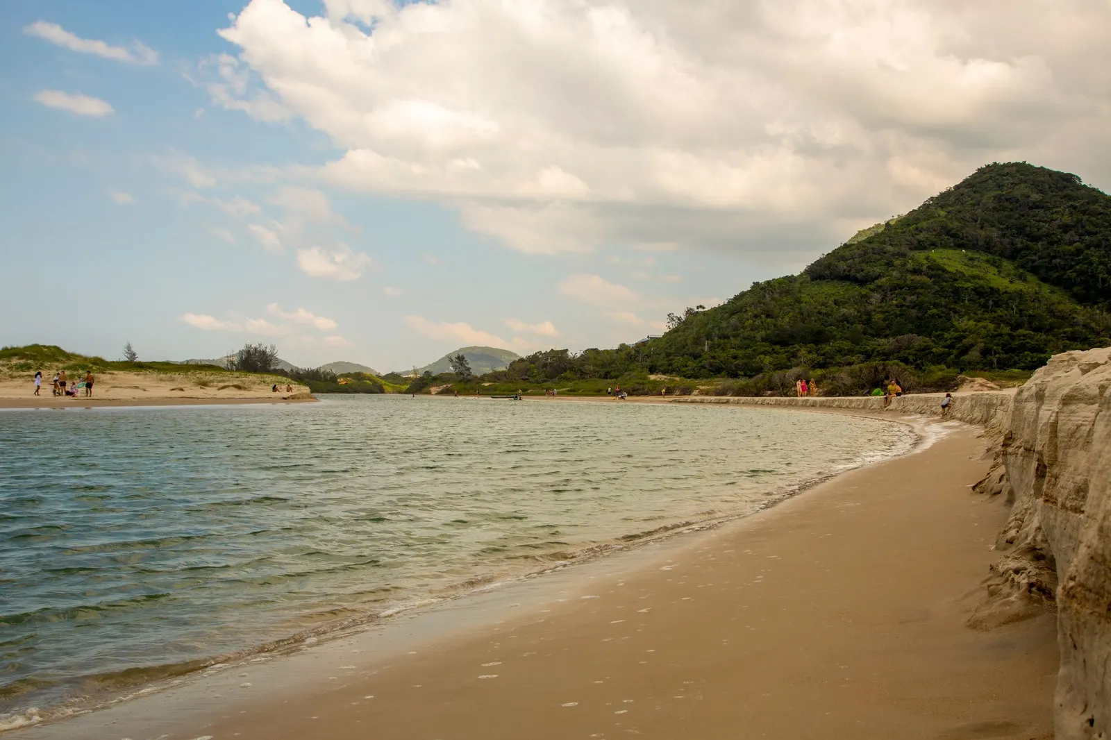 Praia de Garopaba com morros verdes e céu nublado